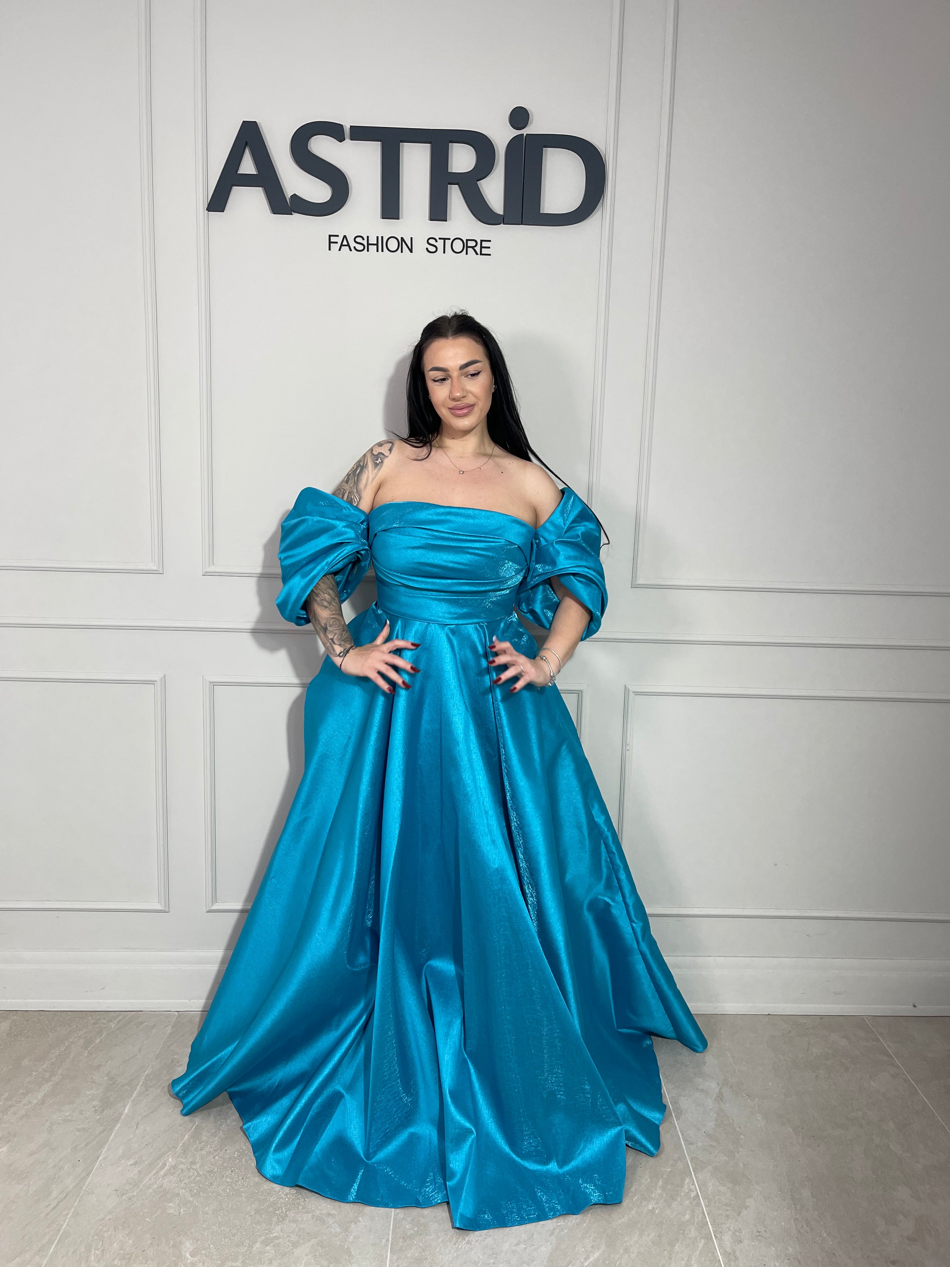 Rochie Lora lungă, intr-un albastru deschis delicat, cu umeri goi ce subliniază eleganța și feminitatea.