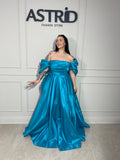 Rochie Lora lungă, intr-un albastru deschis delicat, cu umeri goi ce subliniază eleganța și feminitatea.