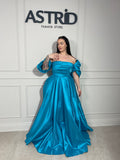 Rochie Lora lungă, intr-un albastru deschis delicat, cu umeri goi ce subliniază eleganța și feminitatea.