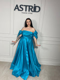 Rochie Lora lungă, intr-un albastru deschis delicat, cu umeri goi ce subliniază eleganța și feminitatea.